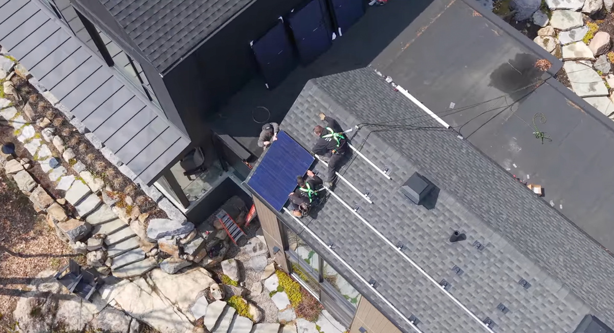Électriciens licenciés installant un panneau solaire sur une toiture