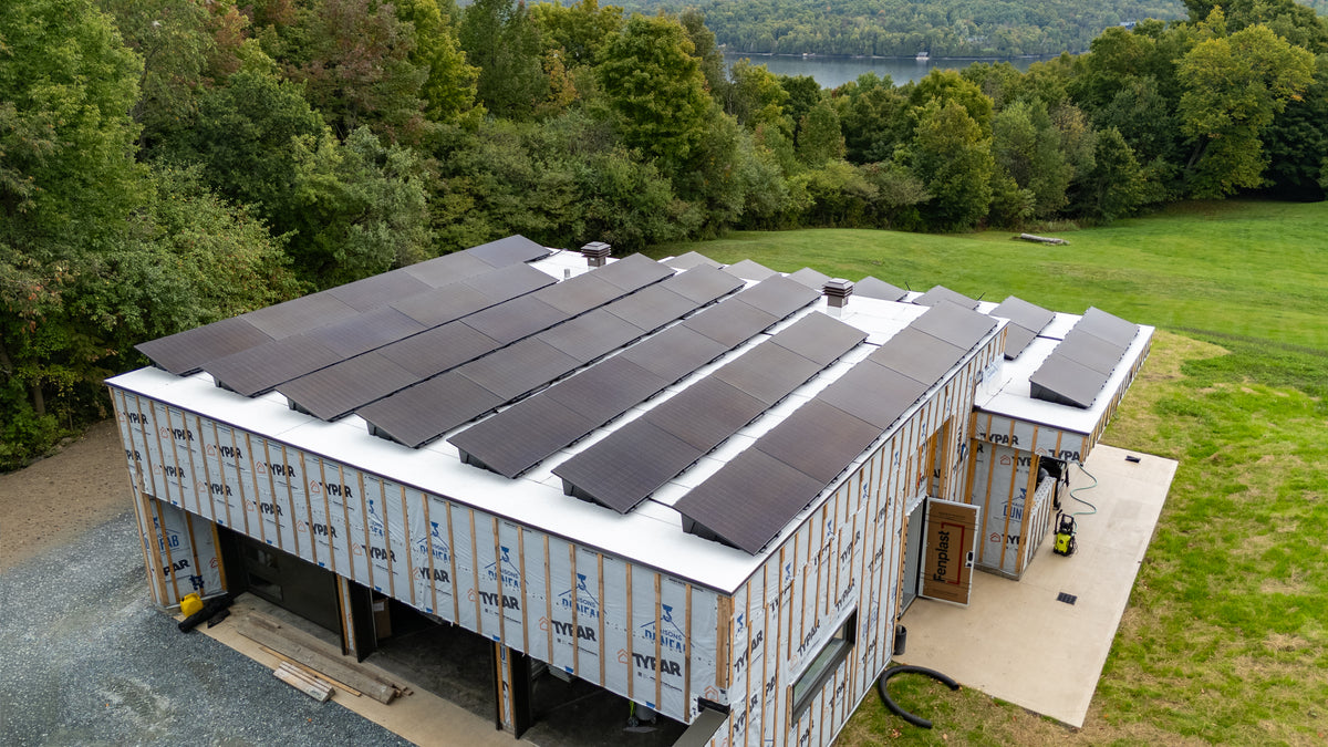 Chantier de construction neuve avec panneaux solaires installés en toiture, vue aérienne en Estrie